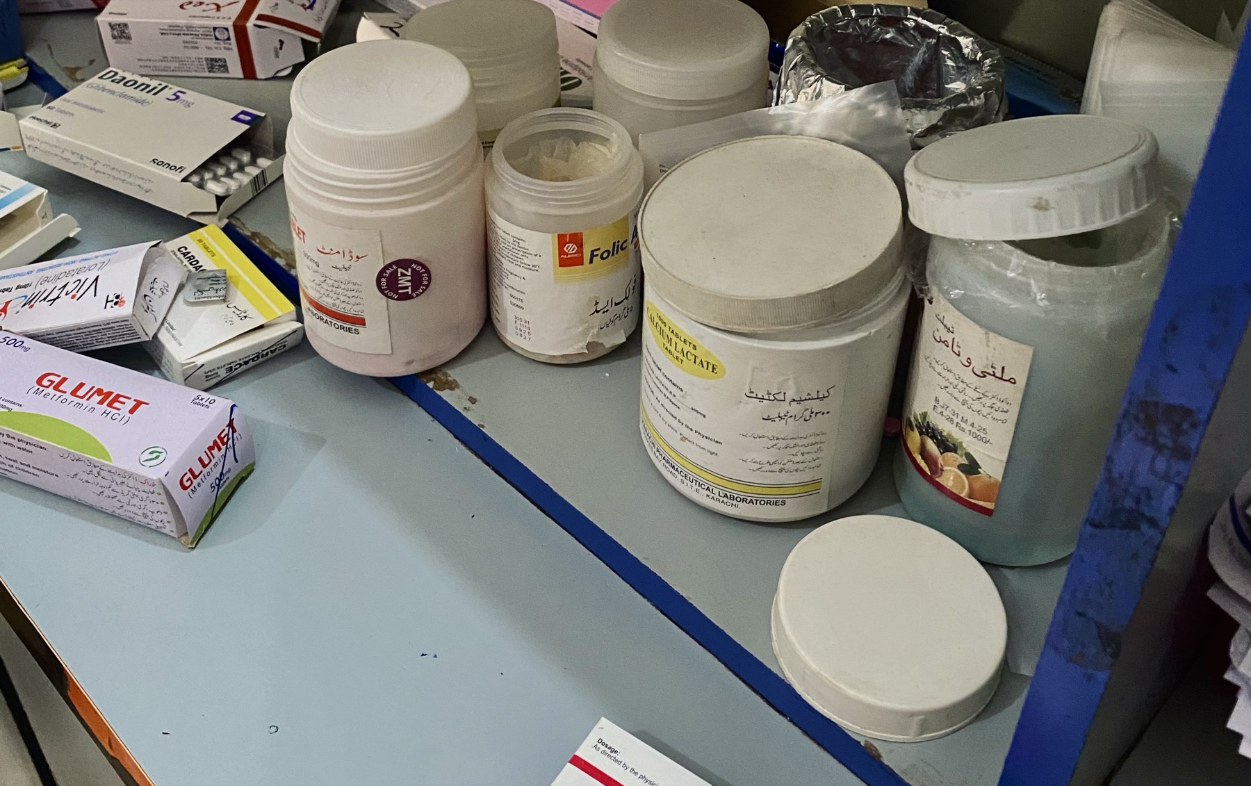Prenatal supplements, including folic acid and calcium lactate, on a pharmacy shelf during field research in Pakistan.